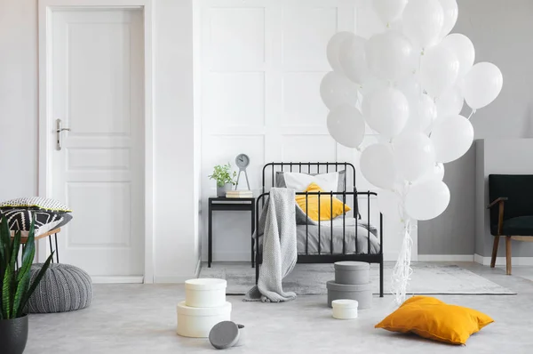 Birthday celebration in white industrial bedroom with metal bed and concrete floor