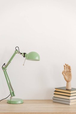 Yığın masa üzerine nane yeşili lamba yanında kitap üzerinde ahşap el