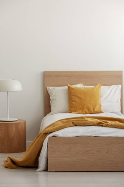 Sarı yastık ve battaniye tek kişilik yatak, kopya alanı boş duvar basit otel odasında beyaz yatak var