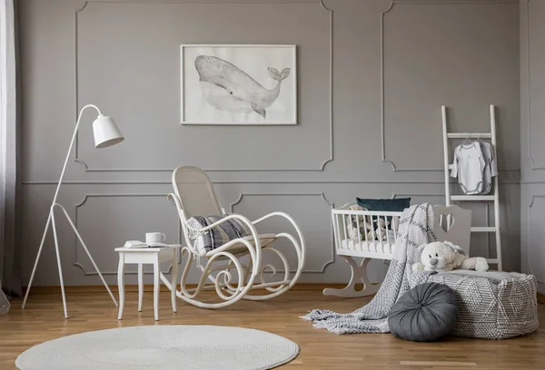 白色摇椅与枕头在舒适的婴儿房间内部的中间 木制摇篮 工业白色灯和海报在框架上的空灰色墙 — 图库照片