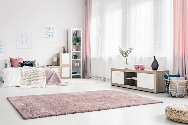 大蓬松的地毯上的优雅卧室内部的白色墙壁与木制的橱柜和柳条篮子 — 图库照片