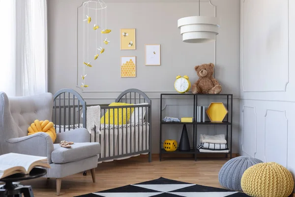 灰色と黄色の赤ちゃんルーム木製ベビーベッド 快適なアームチェア 工業用本棚 — ストック写真