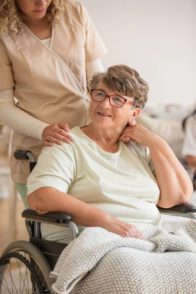 高齢者の特別養護老人ホームで車椅子に座ってフォーム関節炎に苦しんでいる肯定的な老婦人 — ストック写真