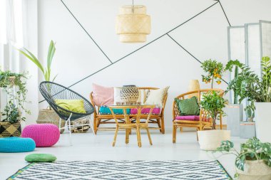 Kentsel ormanda ve şık salon iç rattan koltuk, koltuklar ve sehpa ile birlikte Beyaz ahşap zemin üzerinde desenli halı