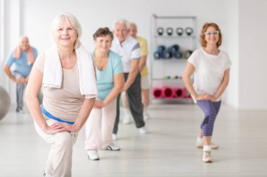 Gülümseyen havlu yaşlı insanlar için fitness dersleri sırasında egzersiz ile üst düzey kadın