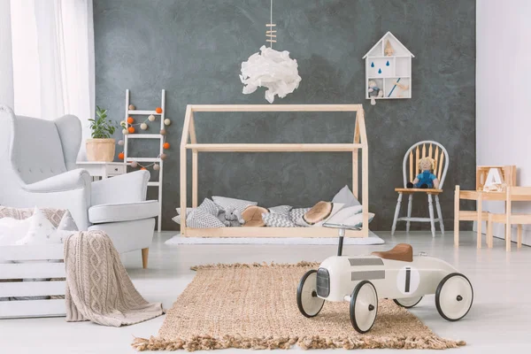 在木床上方的灯在灰色的婴儿的卧室内部与汽车玩具附近的扶手椅 真实照片 — 图库照片