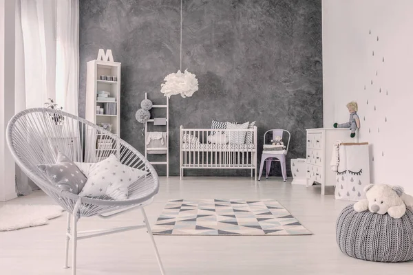 在婴儿卧室内部的 Pouf 上放在灰色扶手上的星垫和毛绒玩具 真实照片 — 图库照片