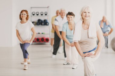 Gülümseyen havlu yaşlı insanlar için yoga dersleri sırasında egzersiz ile üst düzey kadın