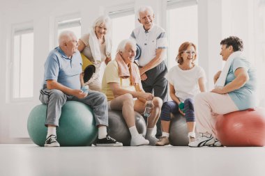 Topları daha önce eğitim parlak fitness merkezinde egzersiz mutlu kıdemli oturma grubu