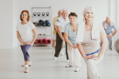 Gülümseyen kıdemli kadın fitness Center'da aktif büyükler grup ile egzersiz