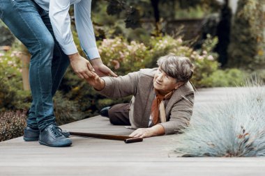 Man helping female senior to get up from the ground clipart