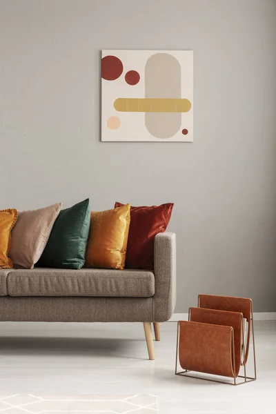 Magazine rack next to beige sofa with pillows in stylish living room interior