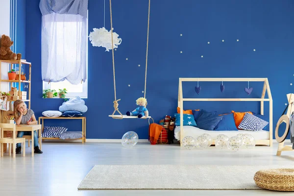 蓝色墙壁与金色的星星在时尚的丑闻锁儿童房间与木制房子形状的床与枕头 — 图库照片