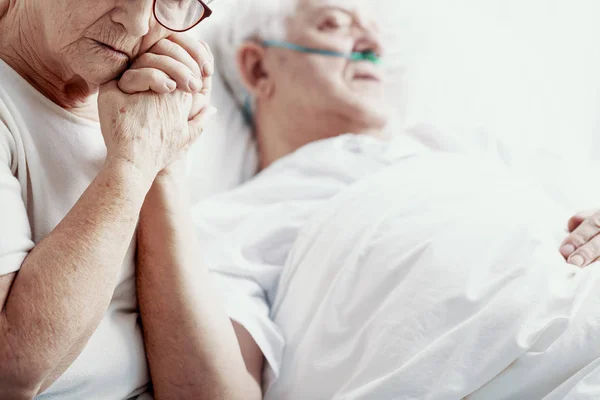 ホスピスのベッドの写真コピー スペースで横になっている彼女は癌病気の夫の手を握って悲しい年配の女性 — ストック写真
