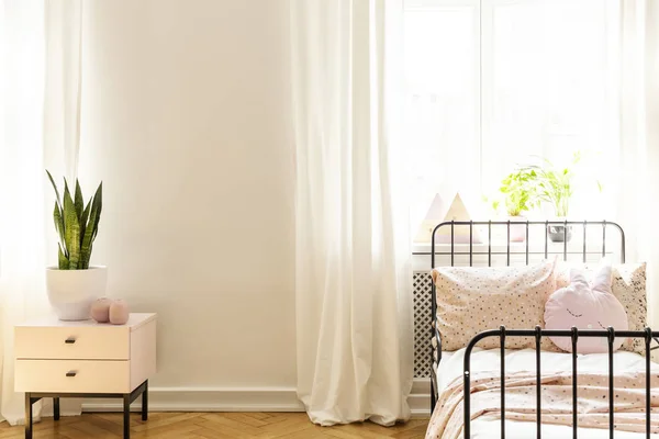ウィンドウの白いシンプルな寝室インテリアの枕が付いているベッドの横にあるキャビネットの植物します 実際の写真 — ストック写真