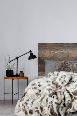 Siyah endüstriyel lamba ve ahşap komidin tabloda gri yatak ve öfke battaniye ile sıcak yatak yanında bitki potu