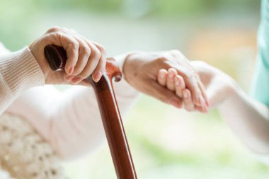 Yaşlı Bayan yürüyüş baston bir elinde tutan ve diğer gönüllü'nın elini tutarak closeup