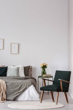 Beyaz yatak odası iç posterler yukarıda yatak ile çiçeklerle tablosunun yanındaki koltuk. Gerçek fotoğraf