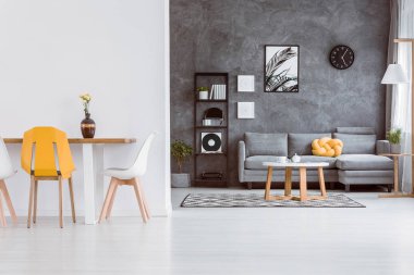 Gri ve beyaz zarif yemek ve ahşap masa şık sandalyeler ve gri sarı düğüm yastık kanepeyle yatak odası