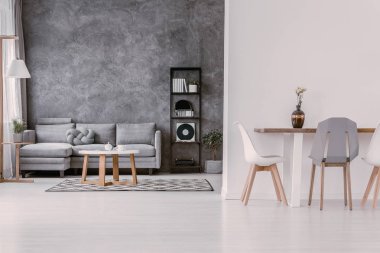 Gri ve beyaz şık yemek ve oturma odası, modern sandalye ve pastel gri düğüm yastık ile gri kanepe ile ahşap masa