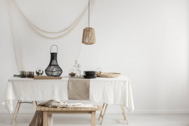 Rattan lamba yemek masası hasır Yaylası ve siyah cam plakanın ve zarif metal fener, kopya alanı boş beyaz duvar ile yukarıda