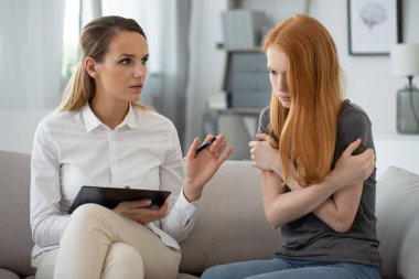 Professional therapist with young teenage red head girl during psychotherapy clipart