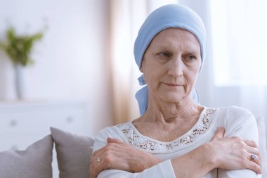 Mavi başörtüsü giyen kıdemli üzgün kadın, evde tek başına oturan kemik kanseri muzdarip
