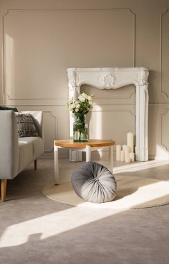 Mum ile beyaz şömine ile gri oturma odası iç yuvarlak ahşap sehpa üzerinde cam vazo gül, duvarda kopya alanı