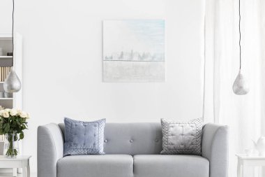 Beyaz mobilya üzerinde gri kanepe ve gümüş lambalar ile lüks oturma odası duvarında soyut boyama