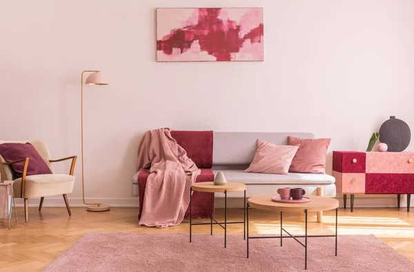抽象勃艮第和柔和的粉红色画在白色的墙壁上的时尚客厅内部与优雅的扶手椅和时尚的沙发 — 图库照片