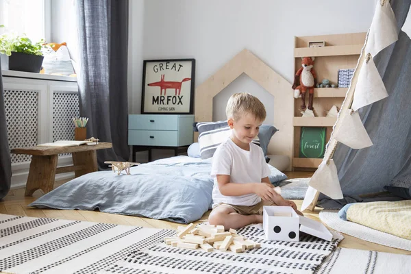 スカンジナビアのデザイン 実際の写真とスタイリッシュなベッドルームで木製のブロックで遊んでかわいい男の子 — ストック写真