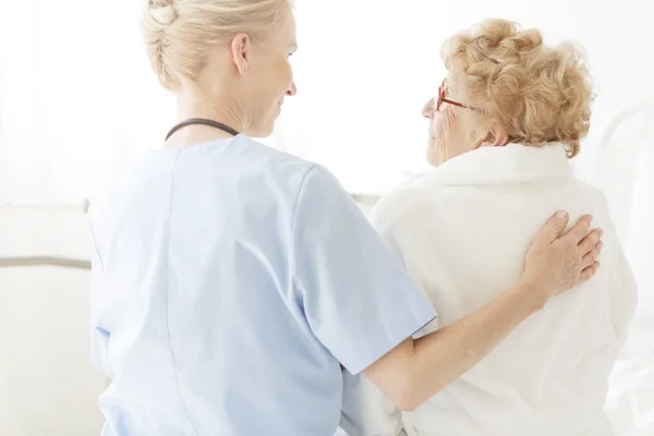 Infermiera Utile Seduta Letto Ospedale Accanto Una Donna Più Anziana — Foto Stock