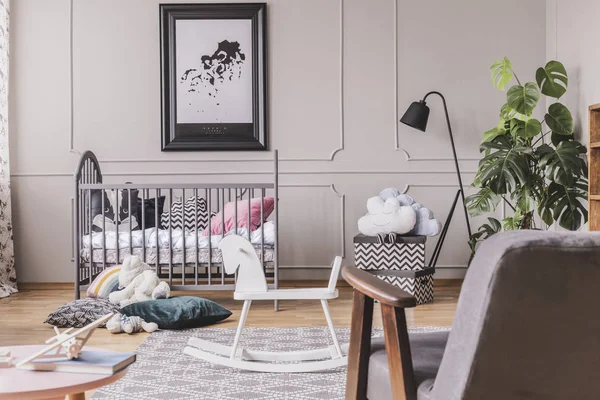 Caballo balancín y juguetes delante de la cama en el interior del dormitorio del bebé con cartel y lámpara. Foto real —  Fotos de Stock