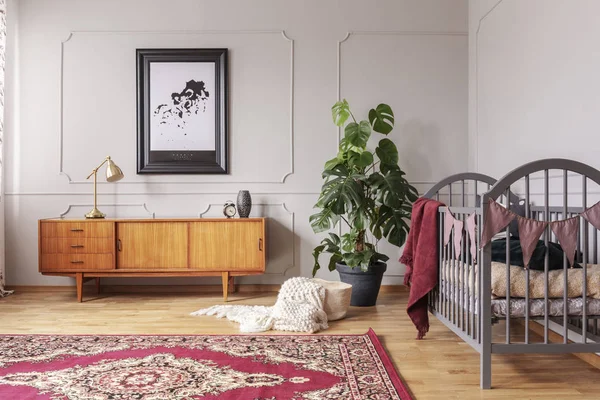 Armario de madera retro en el interior del dormitorio de bebé gris con planta monstruo en maceta negra y cuna de madera, foto real con póster en la pared —  Fotos de Stock