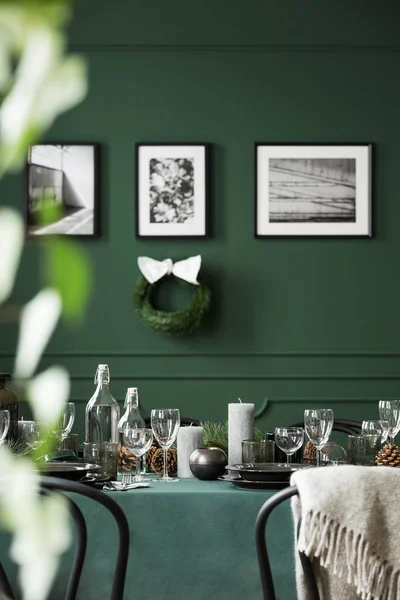 Christmas garland and black and white posters on green wall of dining room set for christmas dinner — Stock Photo, Image