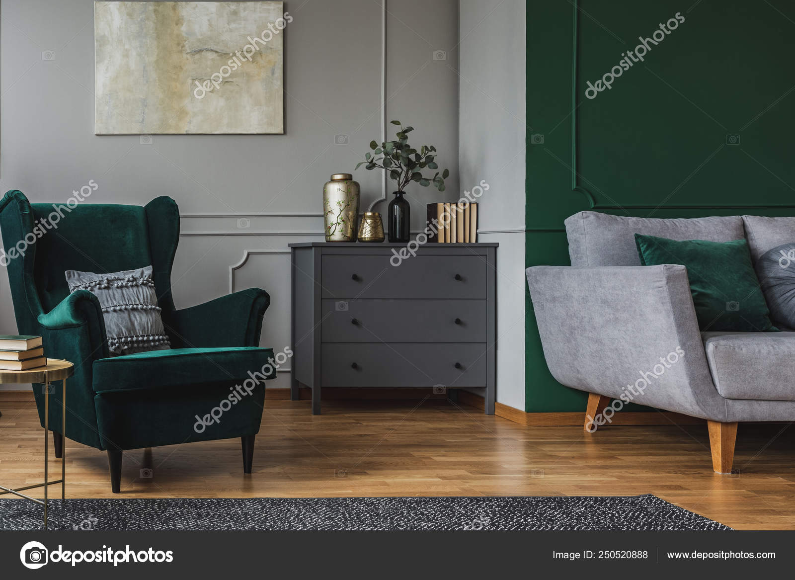 emerald green armchair with pillow next to grey wooden commode in dark  living room interior 250520888