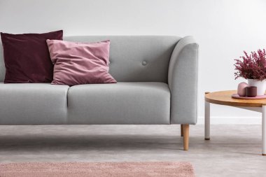 Parlak oturma odası iç yastıklar ile gri set yanında ahşap masada Heather. Gerçek fotoğraf