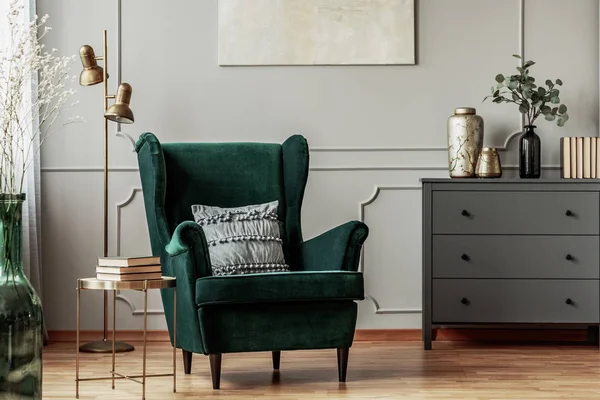 Fauteuil vert émeraude avec oreiller à côté de la commode en bois gris dans le salon sombre intérieur — Photo