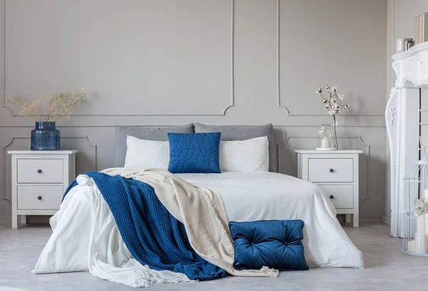 stock image Grey, white and blue pillows and blanket on king size bed in elegant bedroom with copy space