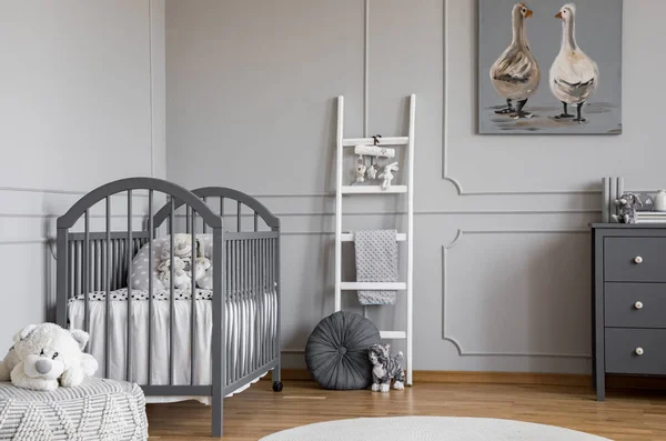 Peluche de peluche en puf frente a cama gris en el interior del dormitorio infantil con escalera y póster. Foto real — Foto de Stock