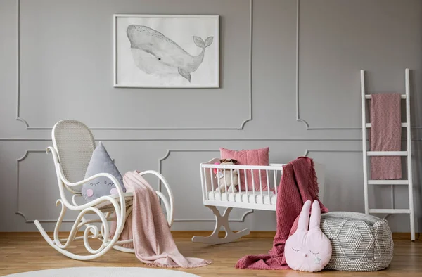 Manta rosa sobre mecedora junto a cuna en el interior del dormitorio infantil gris con póster. Foto real — Foto de Stock