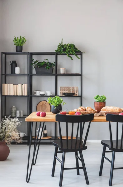 Riktigt foto av en grå matsal interiör med metall hyllor, mat bord med mat och stolar — Stockfoto