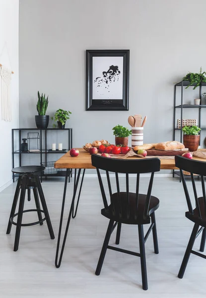 Foto reale di un tavolo da pranzo con cibo, sedie nere e pittura su una parete all'interno di una sala da pranzo — Foto Stock