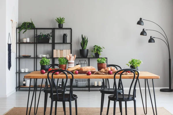 Foto nyata interior ruang makan yang nyaman dengan meja penuh sayuran dan herbal, dan rak hitam di latar belakang — Stok Foto