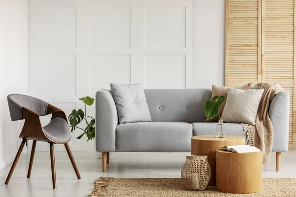 Moderne fauteuil naast een sofa en houten salontafels in een woonkamer interieur — Stockfoto