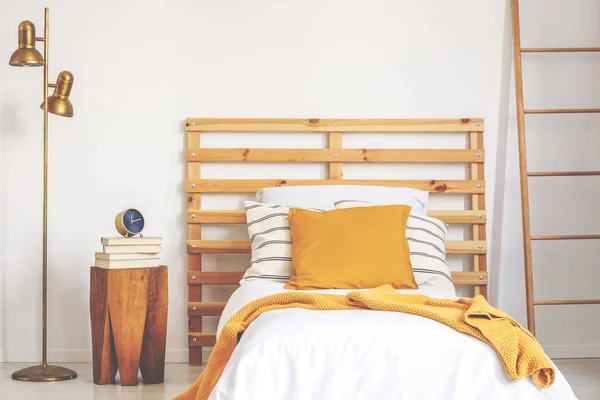 Almohada amarilla y manta en una cama individual de madera blanca en un dormitorio natural, foto real — Foto de Stock