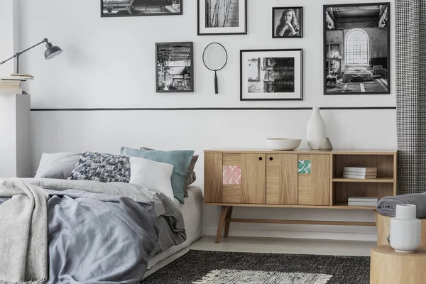 Armoire en bois unique à côté d'un lit confortable avec oreillers et couette grise — Photo
