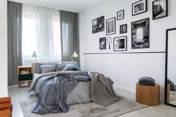 Tende a quadretti sulla finestra della camera da letto contemporanea interno con comodino in legno e letto king size con biancheria da letto grigia — Foto Stock