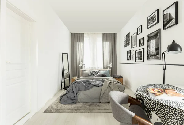 Mesa con mantel de puntos en el interior del dormitorio luminoso con pared blanca —  Fotos de Stock