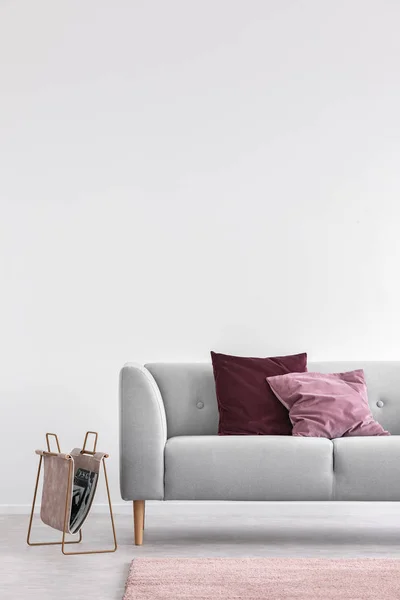 Μαξιλάρια σε γκρίζο καναπέ και ροζ χαλί σε λευκό σαλόνι εσωτερικό με Φωτοτυπικό χώρο. Πραγματική φωτογραφία — Φωτογραφία Αρχείου
